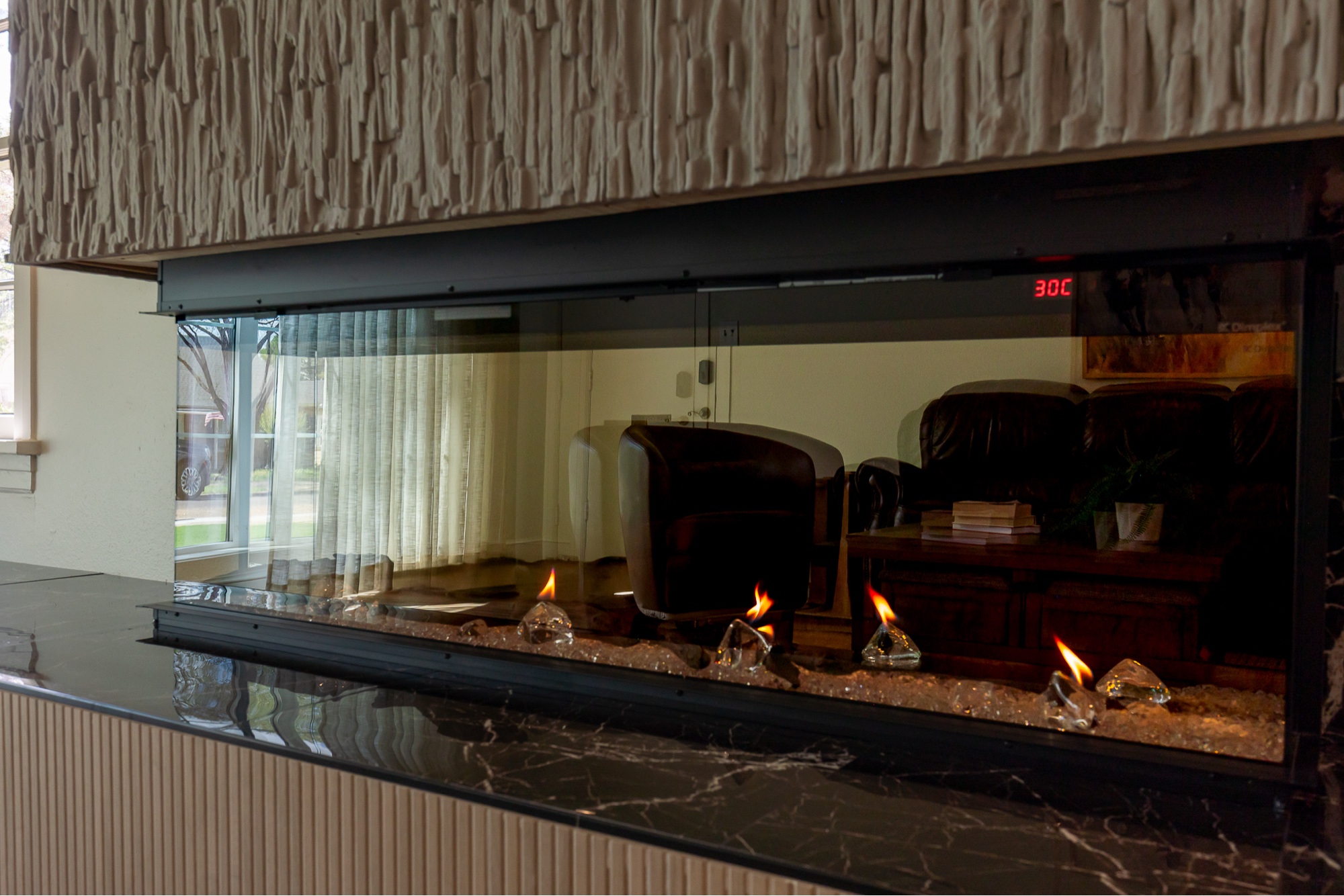 Linear electric fireplace with glass crystals and stone hearth