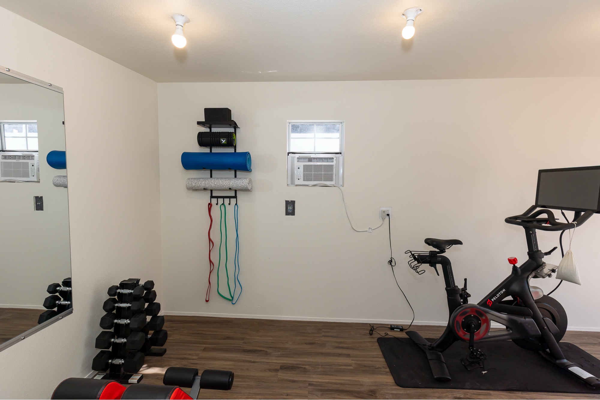 Gym detail with dumbbell rack, mirror wall, and yoga mats