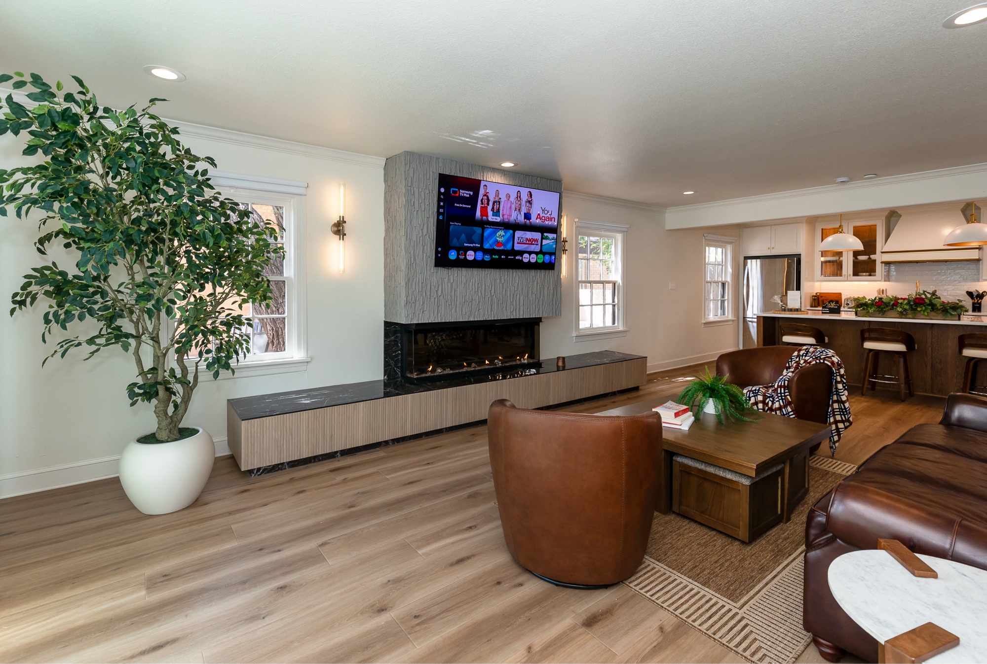 Main living room with linear electric fireplace and open kitchen beyond